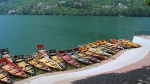 A lakeside view with a row of small boats docked along the shore. - Fredy's Bungalow (Nainital)