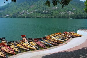 A lakeside view with a row of small boats docked along the shore.