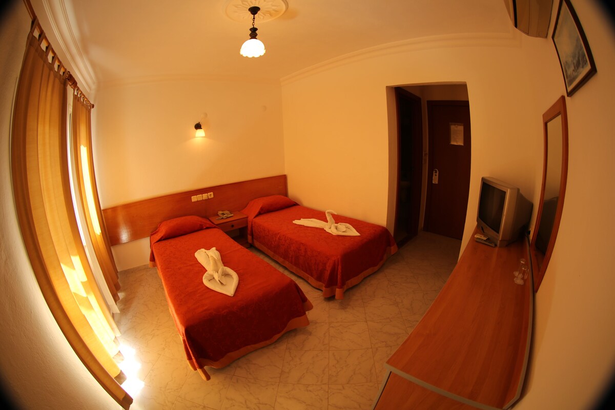 A hotel room with two beds, a TV, and a desk.