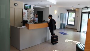 Un espace d’accueil comprenant un bureau, une horloge, un téléviseur et une fenêtre.