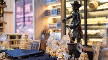 A bakery display with bread and pastries, a statue of a man with a hat, and a chalkboard sign.