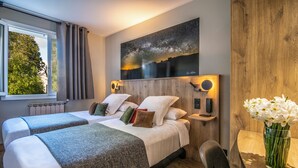 A hotel room with two beds, a night sky mural, a wooden headboard, a bedside table with a lamp, and a window with curtains. - Logis Hôtel l'Aubrac (Laguiole)