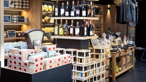 A store with shelves of wine bottles, wooden crates of lollipops, and various packaged goods. - Logis Hôtel l'Aubrac (Laguiole)