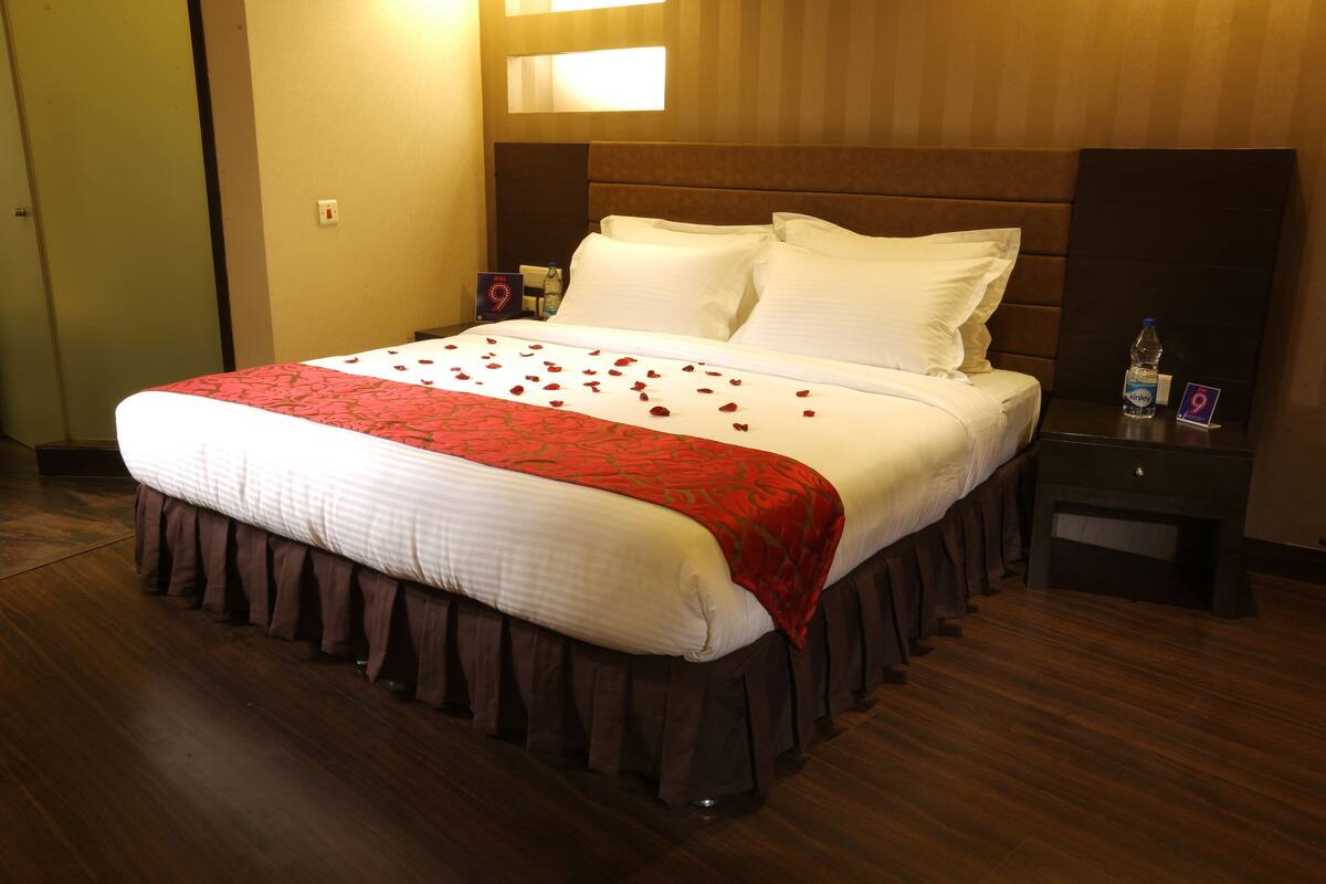 A hotel room with a large bed, a nightstand, a water bottle, and a sign indicating room number 9.