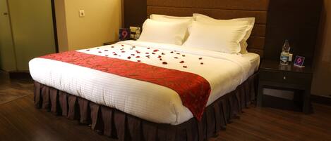 A hotel room with a large bed, a nightstand, a water bottle, and a sign indicating room number 9.