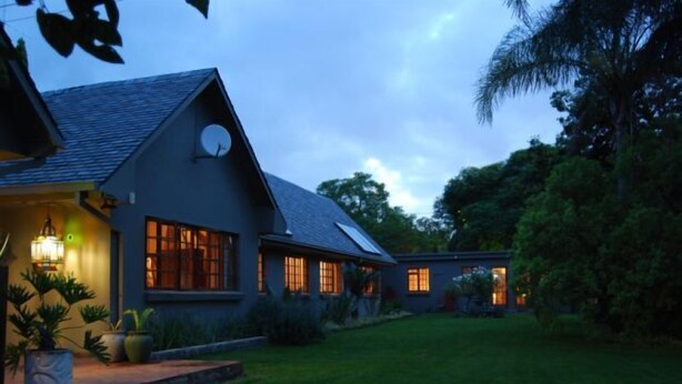 Ein modernes Haus mit großem Rasen, Satellitenschüssel und gut beleuchtetem Eingang.