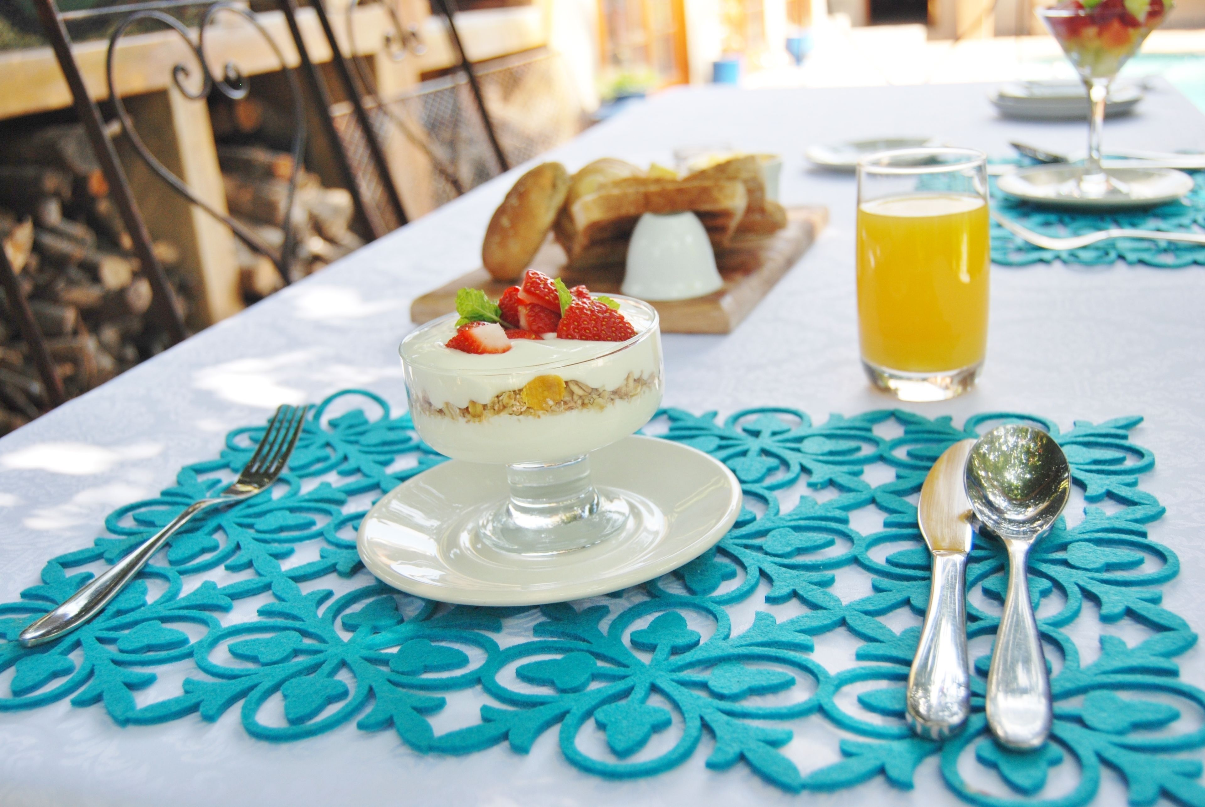 A breakfast setting with a dessert, toast, and a glass of orange juice on a table with a blue tablecloth.