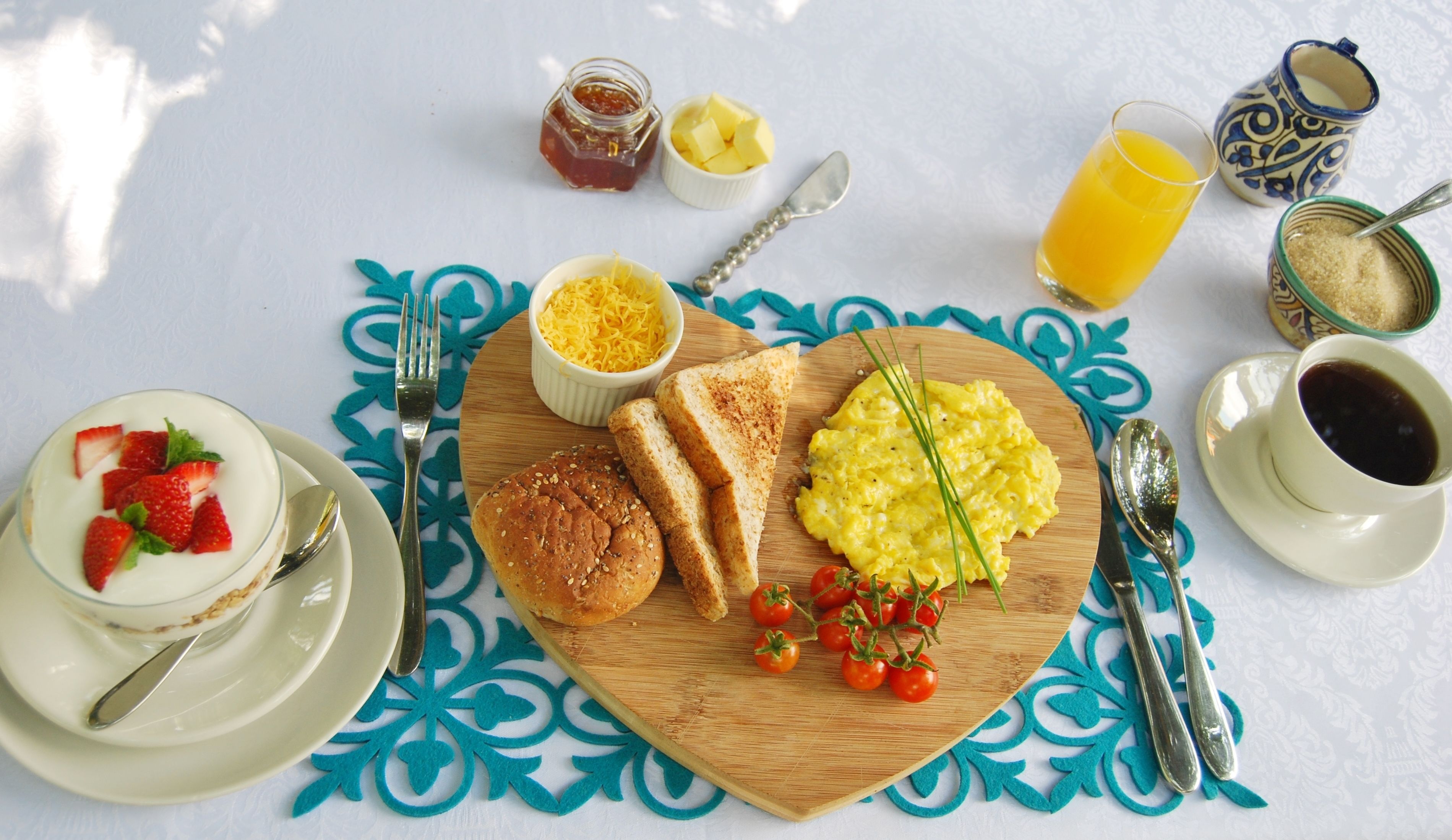 Una mesa de desayuno con una variedad de alimentos, incluyendo tostadas, huevos revueltos y una ensalada de frutas.
