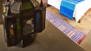 Ein Schlafzimmer mit einem Bett, einem hölzernen Kopfteil, einem Nachttisch, einer Lampe und einer dekorativen Laterne.