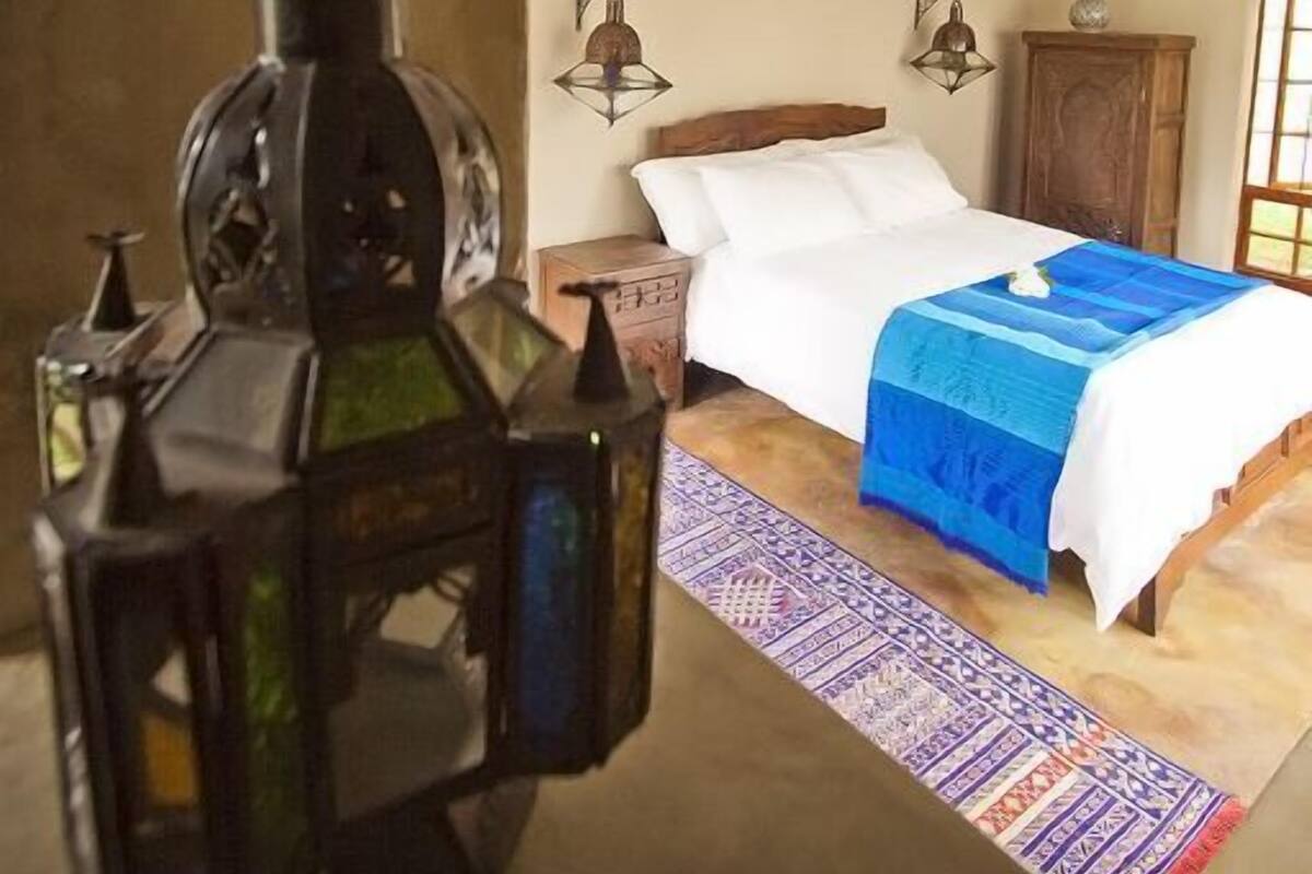 Ein Schlafzimmer mit einem Bett, einem hölzernen Kopfteil, einem Nachttisch, einer Lampe und einer dekorativen Laterne.