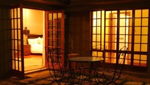 Ein traditioneller japanischer Raum mit Tatami-Böden, einem niedrigen Tisch mit Stühlen und Schiebetüren, beleuchtet von warmem Innenlicht.