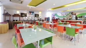 A brightly lit restaurant with multiple tables and chairs, a counter with a display, and a ceiling with recessed lighting. - Dewarna Hotel & Convention (Bojonegoro)