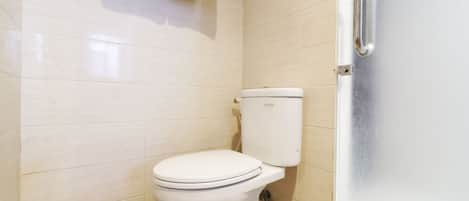 A small, clean bathroom with a white toilet, a towel hanging on the wall, and a door with a handle.