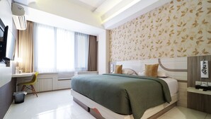 A modern hotel room with a large bed, a desk, and a chair. - Dewarna Hotel & Convention (Bojonegoro)