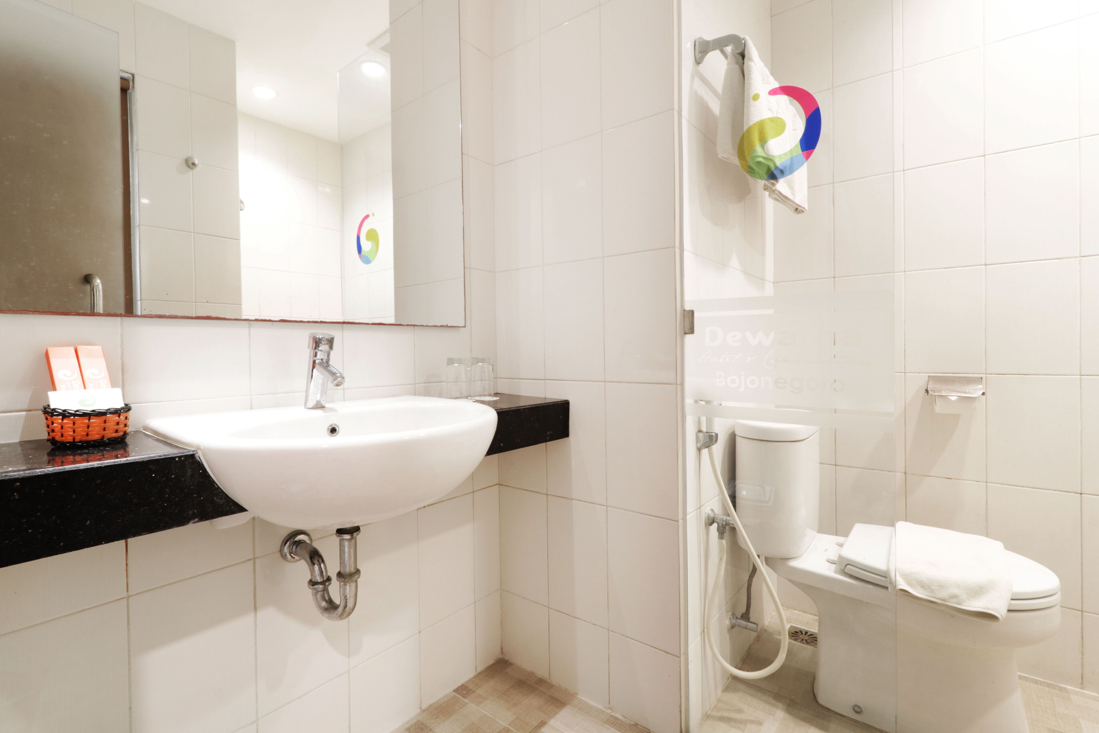 A modern bathroom with a white sink, black countertop, and a toilet.