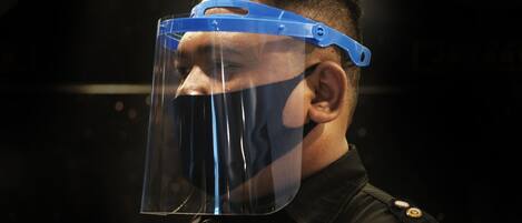 A person wearing a blue face shield and a black jacket with a visible button.