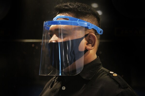 A person wearing a blue face shield and a black jacket with a visible button. - Dewarna Hotel & Convention (Bojonegoro)