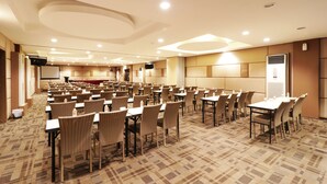 A conference room with rows of tables and chairs, equipped with projectors and a large screen. - Dewarna Hotel & Convention (Bojonegoro)