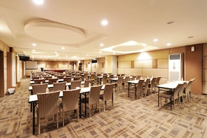 Host meetings and presentations in this well-equipped conference room with tables, chairs, and a large screen.