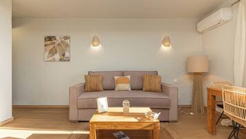 A living room with a sofa, a coffee table, a lamp, and a wall-mounted air conditioner.