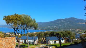 A coastal property with stone walls, a stone pathway, and a view of the sea and a mountain.