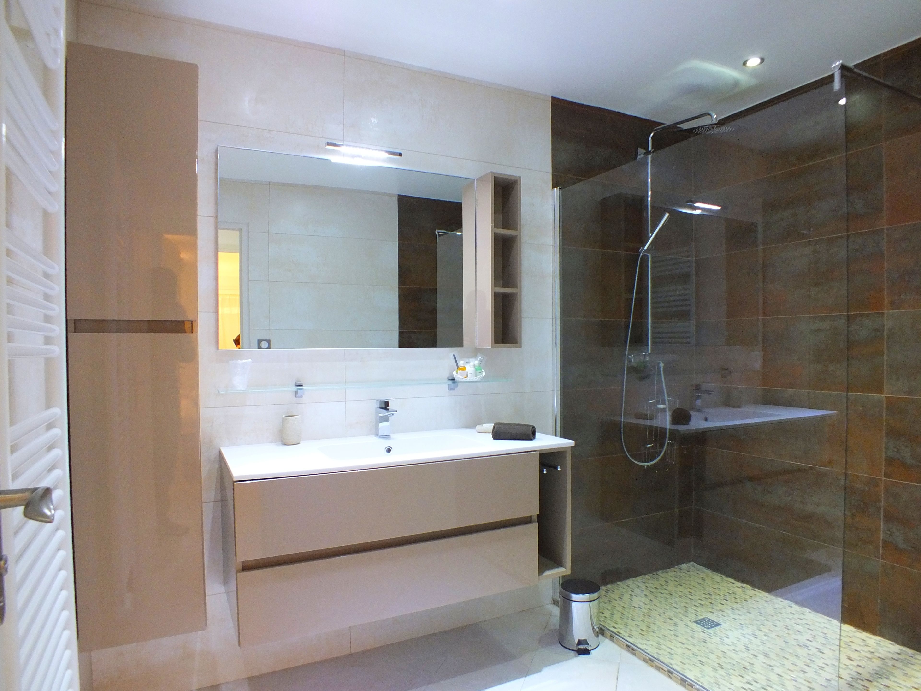 Un baño moderno con un espejo grande, un lavabo y una ducha.