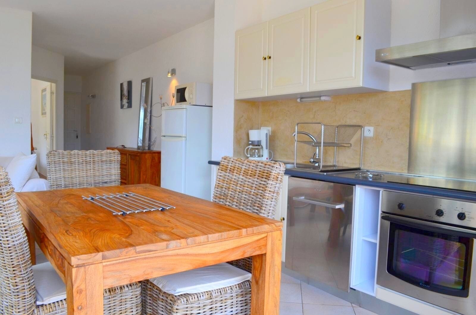 A compact kitchen with white cabinets, a stainless steel oven, and a microwave.