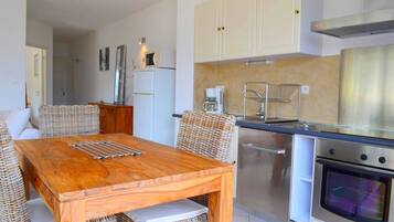 A compact kitchen with white cabinets, a stainless steel oven, and a microwave.