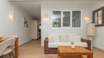 A modern living room with a sofa, coffee table, and dining area.