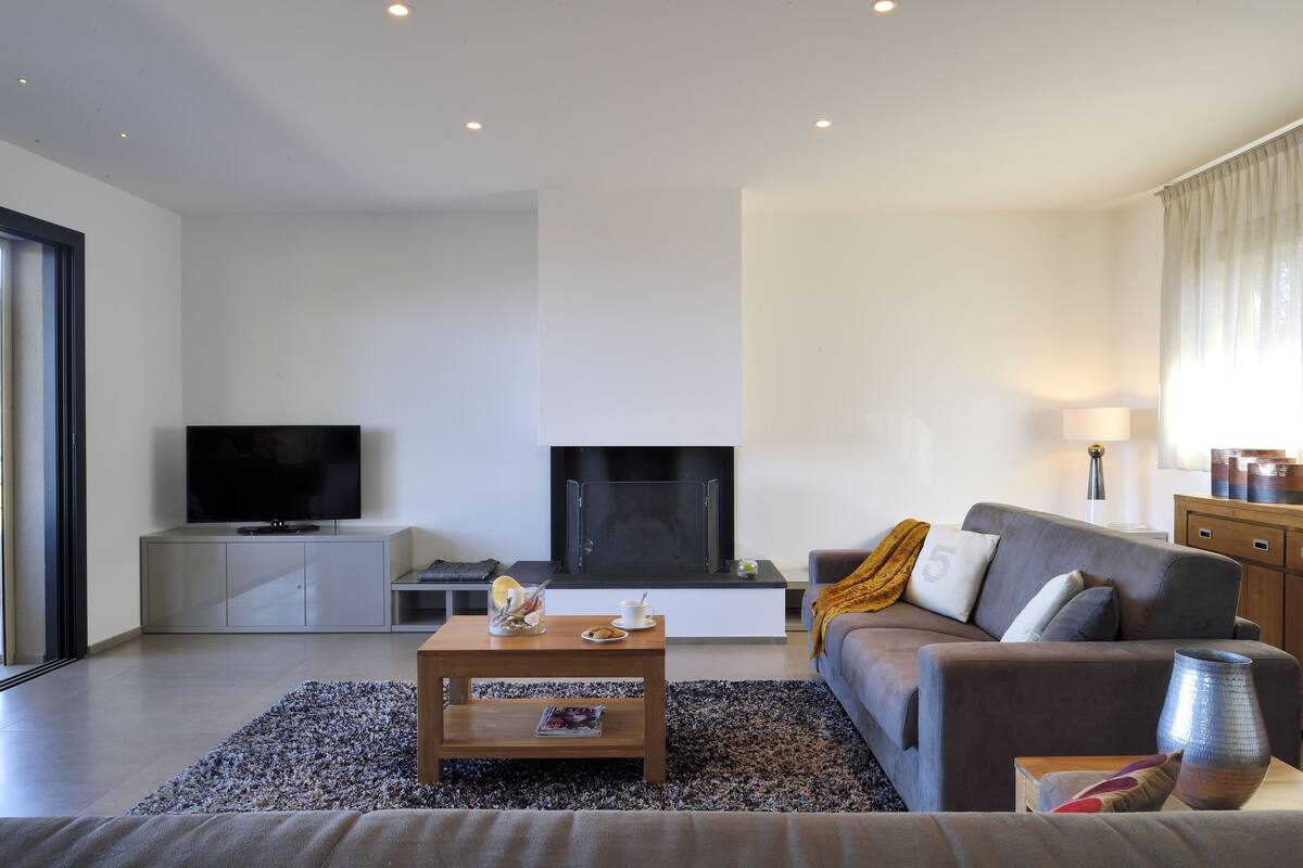 A modern living room with a flat-screen TV, a fireplace, a sofa, and a coffee table.
