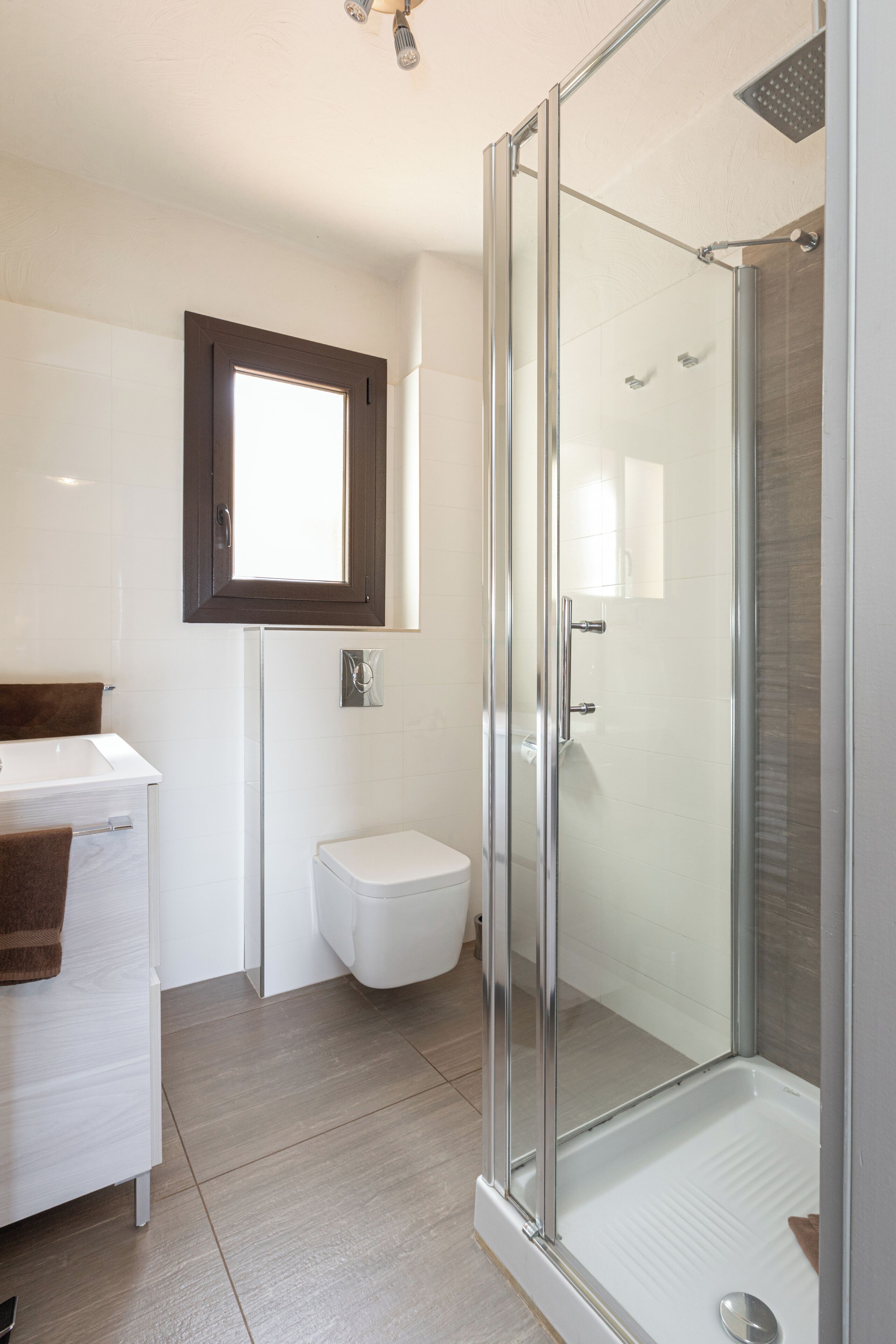 A modern bathroom with a glass-enclosed shower, a white sink, and a toilet.