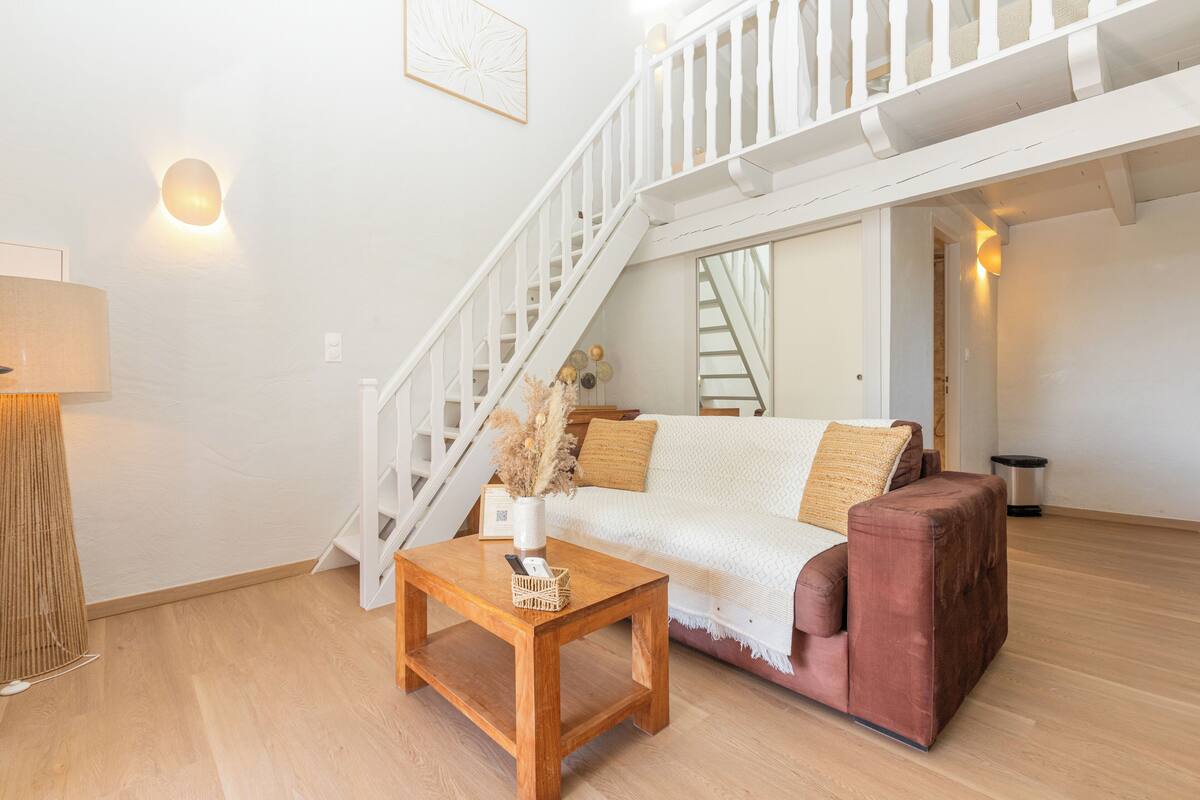 A living room with a wooden coffee table, a sofa, a staircase, and a wall-mounted light fixture.