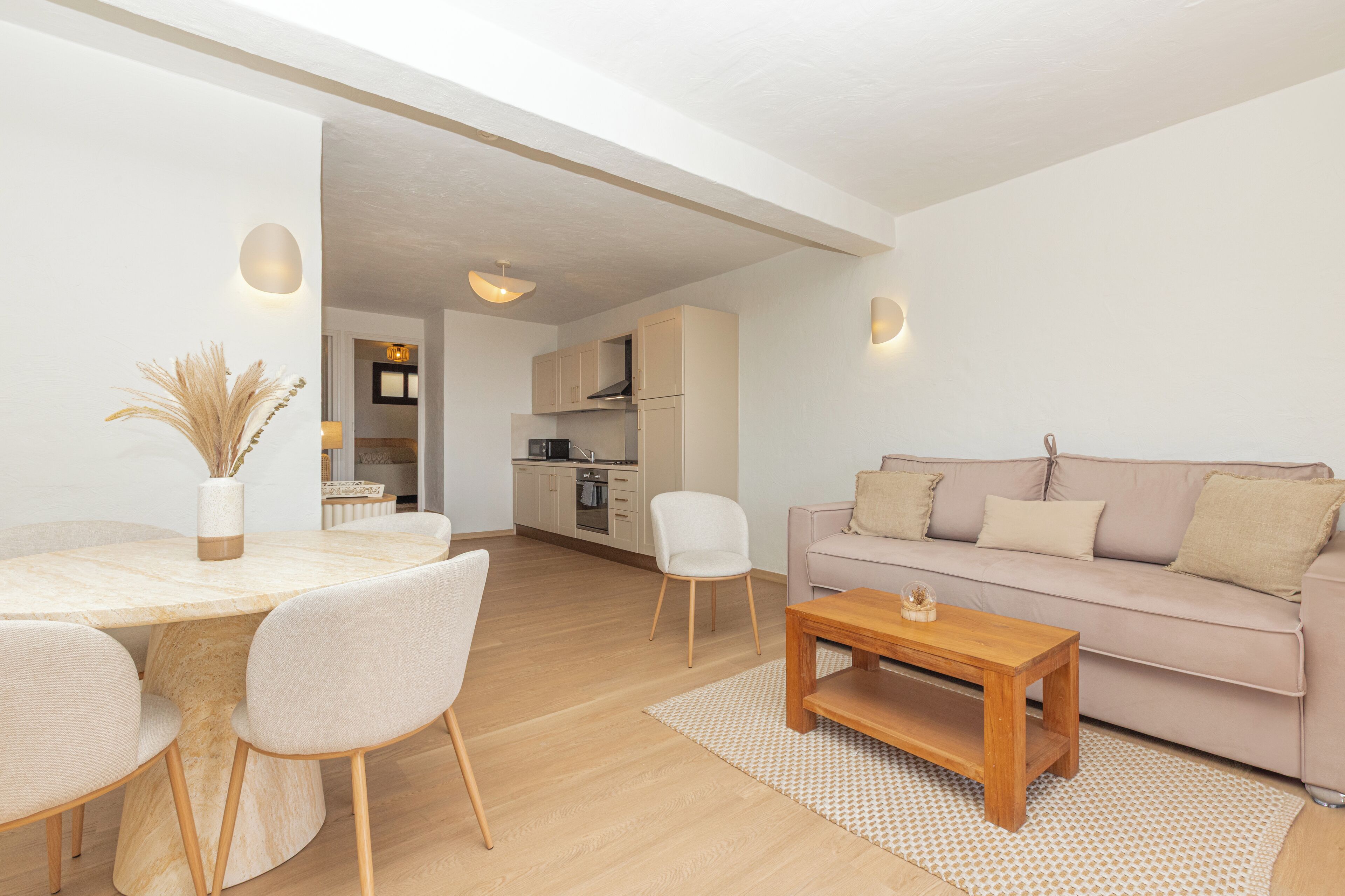 Una sala de estar moderna con una mesa redonda de comedor, un sofá y una cocina al fondo.