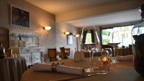Une table à manger dressée avec une serviette pliée, un verre à vin, une bougie et un pichet.