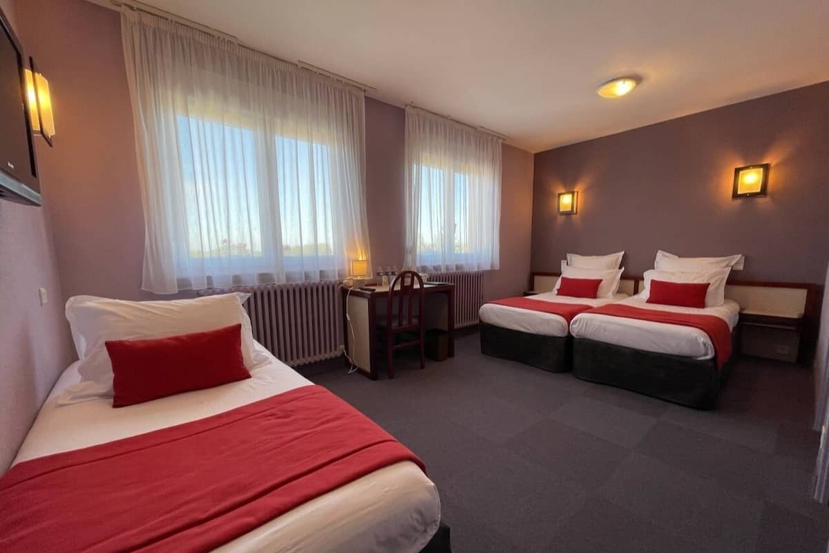 Habitación de hotel con dos camas, un escritorio y una silla.