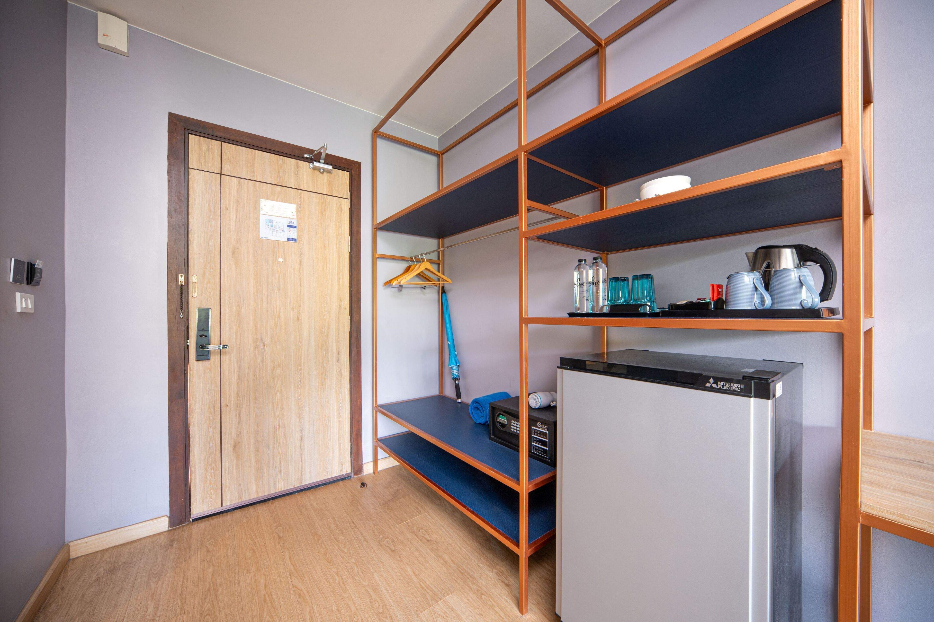 A compact kitchen with a built-in refrigerator, wooden shelving, and a blue countertop.