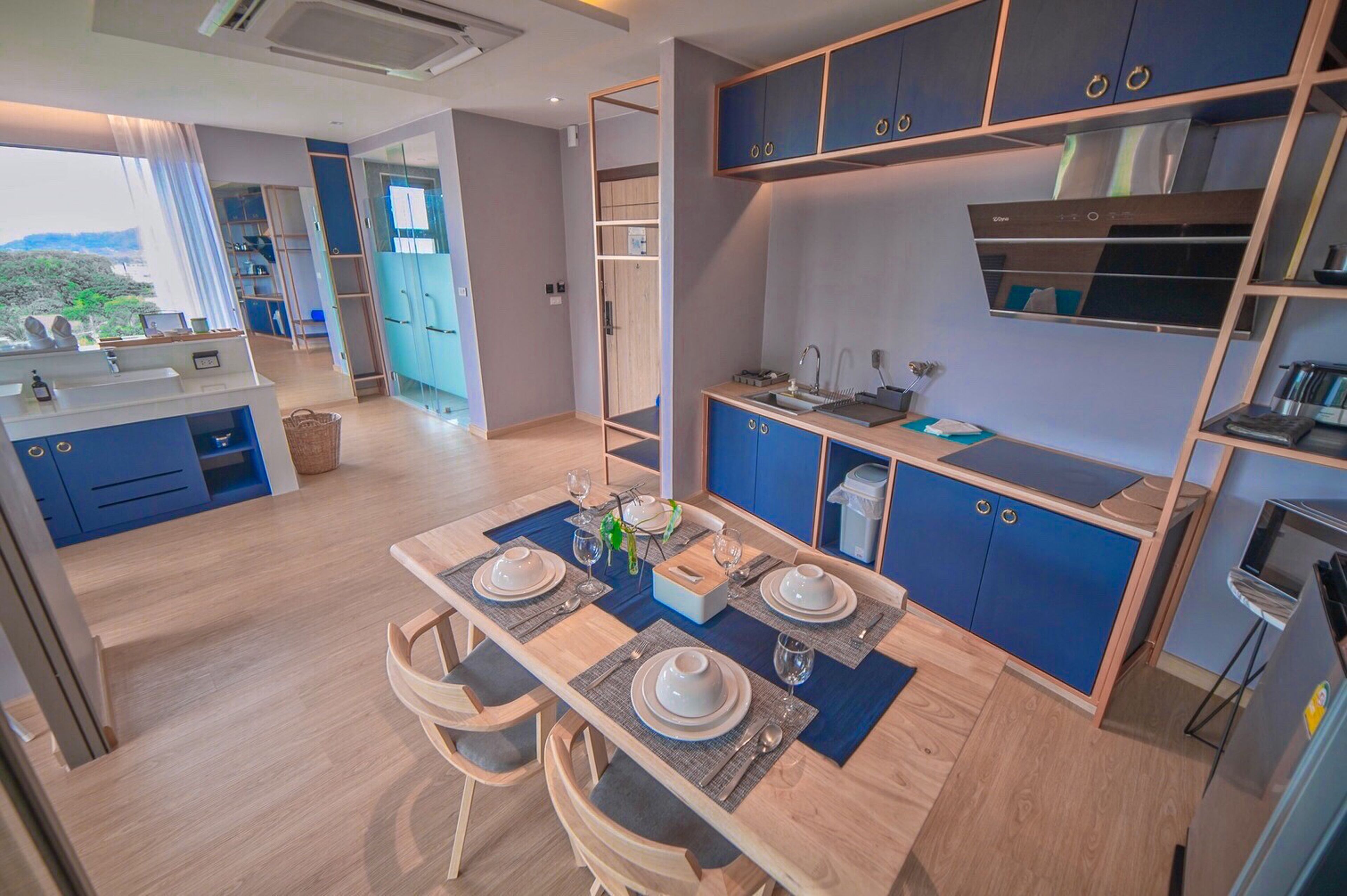 A modern kitchen with blue cabinets, a dining area with a table set for four, and a view of the outdoors.