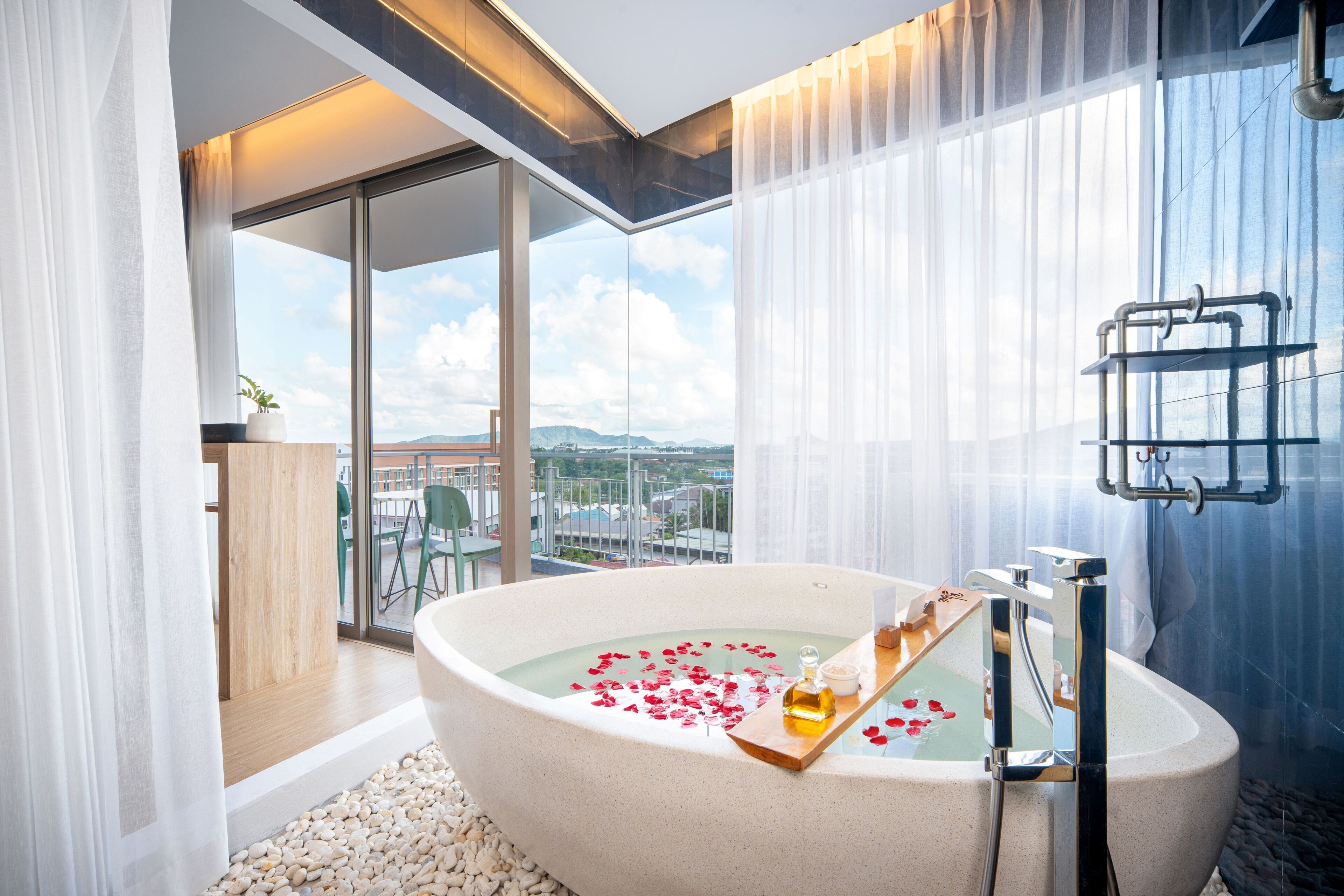 A modern bathroom with a freestanding bathtub, a glass shower enclosure, and a view of the city through large windows.
