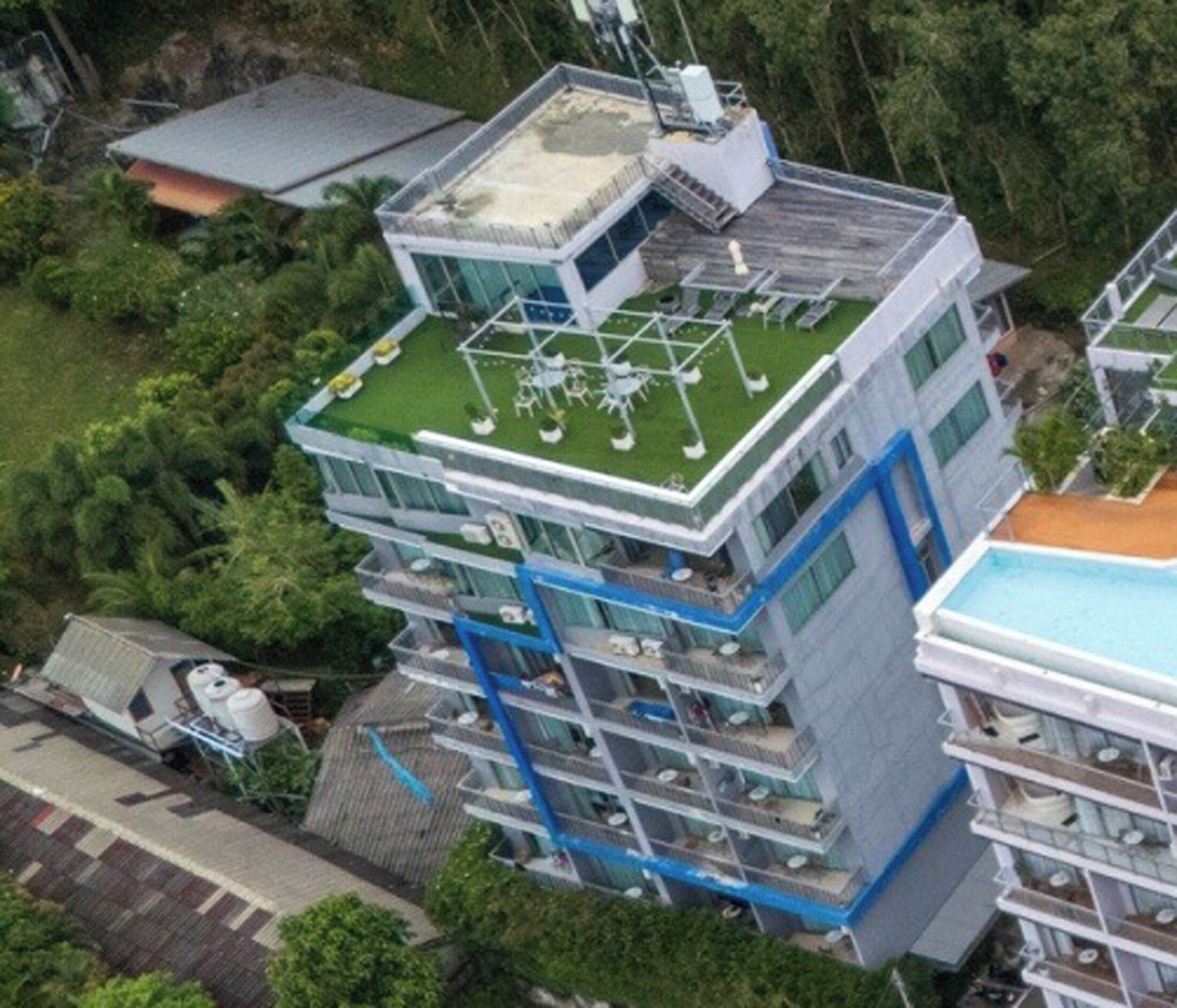 A multi-story building with a rooftop terrace, balconies, and a swimming pool.