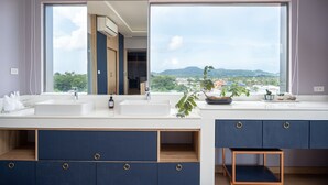 A modern bathroom with two sinks, a large mirror, and a view of a cityscape through large windows. - The Blue (Chalong)