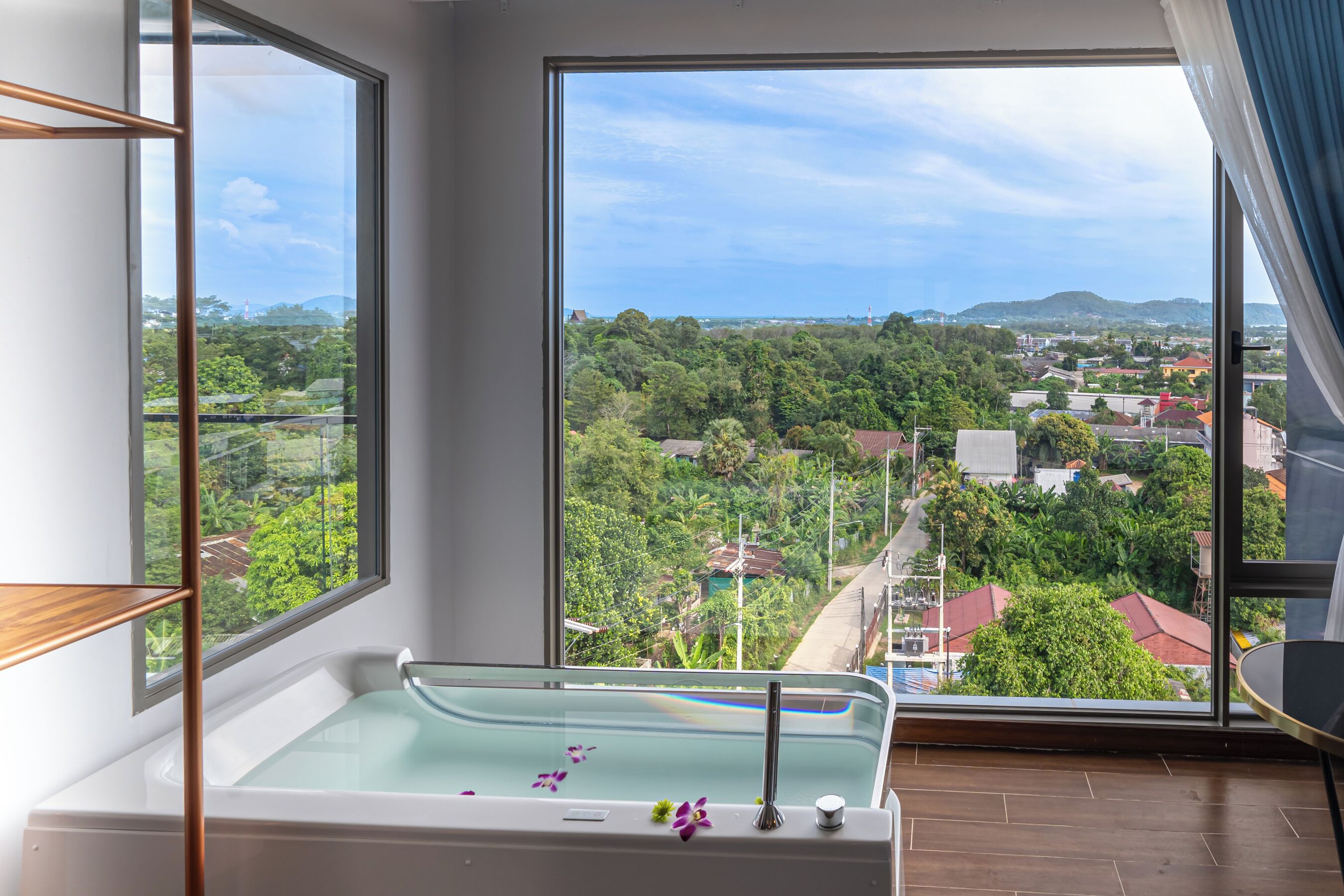Un baño moderno con una bañera grande, vistas a un paisaje verde exuberante y suelo de madera.