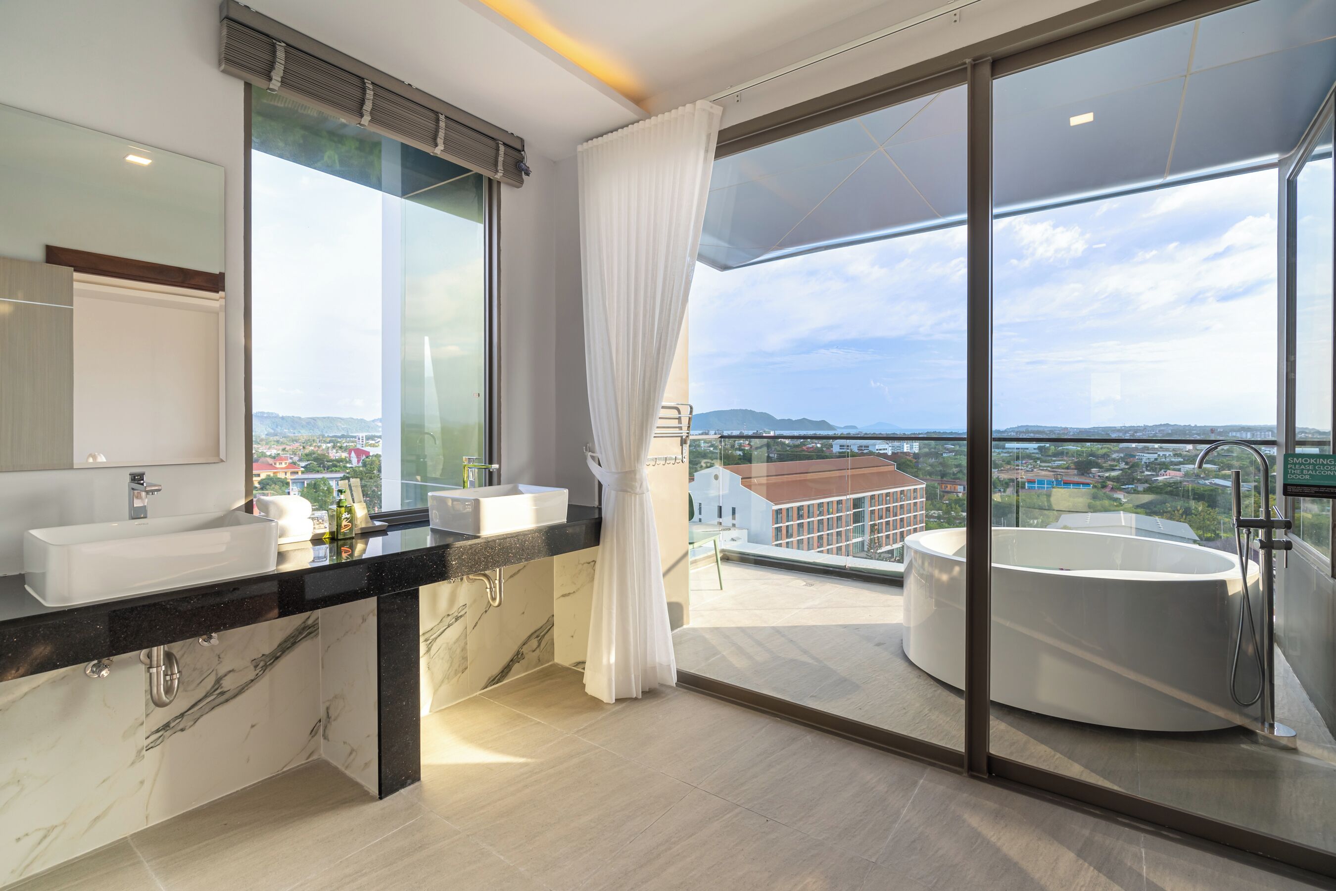 A modern bathroom with a large window, a bathtub, and a vanity with a sink.
