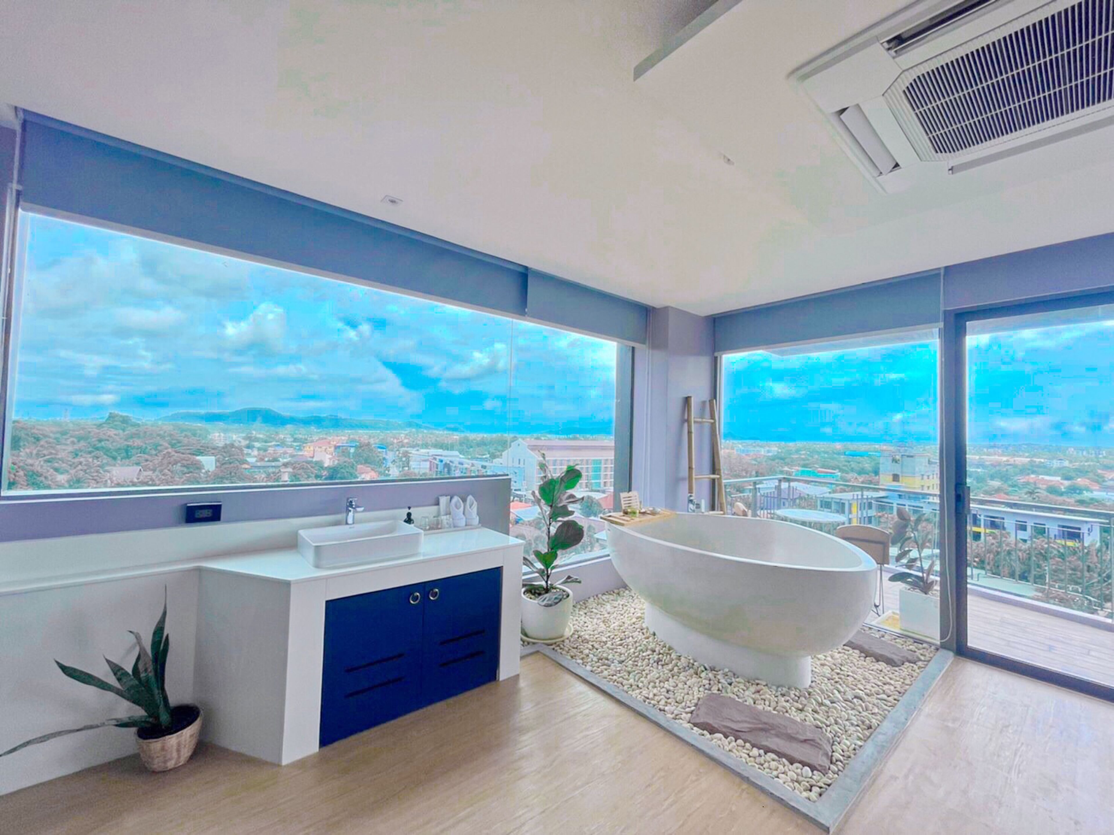 A modern bathroom with a freestanding bathtub, a large window, and a city view.