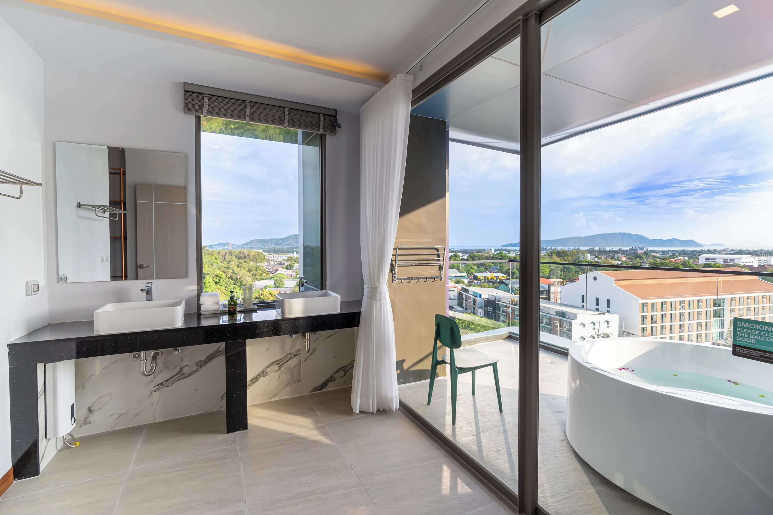 A modern bathroom with a large window, a bathtub, and a view of the city.