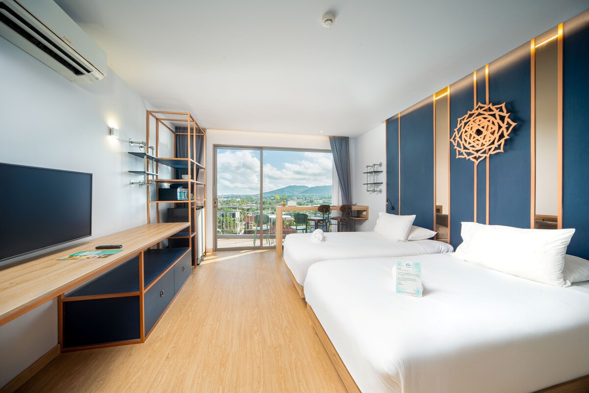 A modern hotel room with a large bed, a desk, and a balcony with a city view.