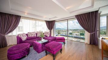 A modern living room with a purple sofa set, a coffee table, and a view of the cityscape through large windows.