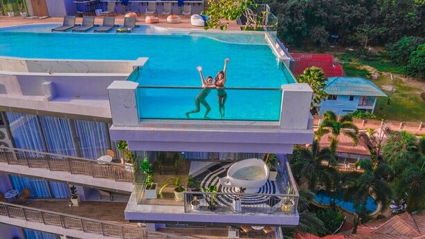 A rooftop pool with a glass barrier, lounge chairs, and a dining area with outdoor seating. - The Blue (Chalong)