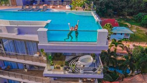 A rooftop pool with a glass barrier, lounge chairs, and a dining area with outdoor seating. - The Blue (Chalong)