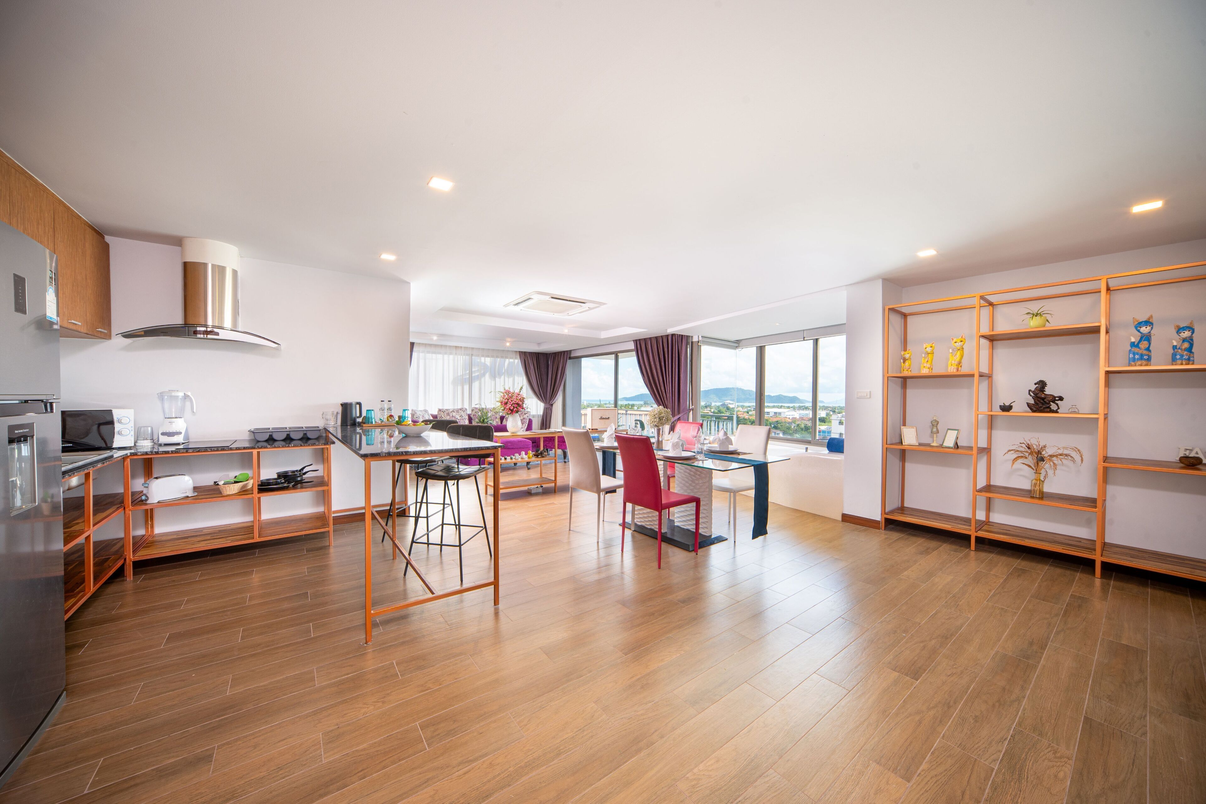 Une cuisine moderne avec un plancher en bois, un coin repas avec une chaise rouge et une grande fenêtre donnant sur un beau paysage.