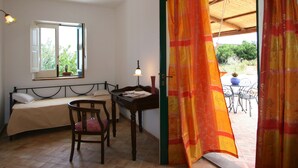 Una habitación con cama, escritorio, silla y ventana, con vistas al exterior.